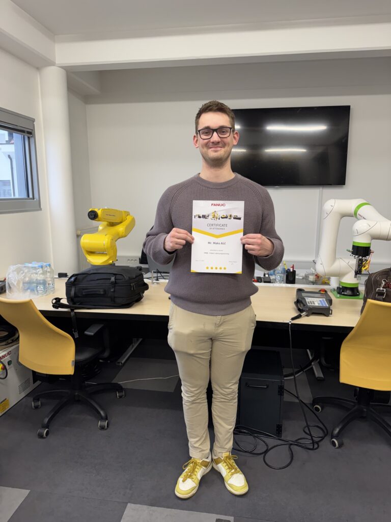 Portrait of Maks Alič holding certificate of attendence for course on programming FANUC robots.